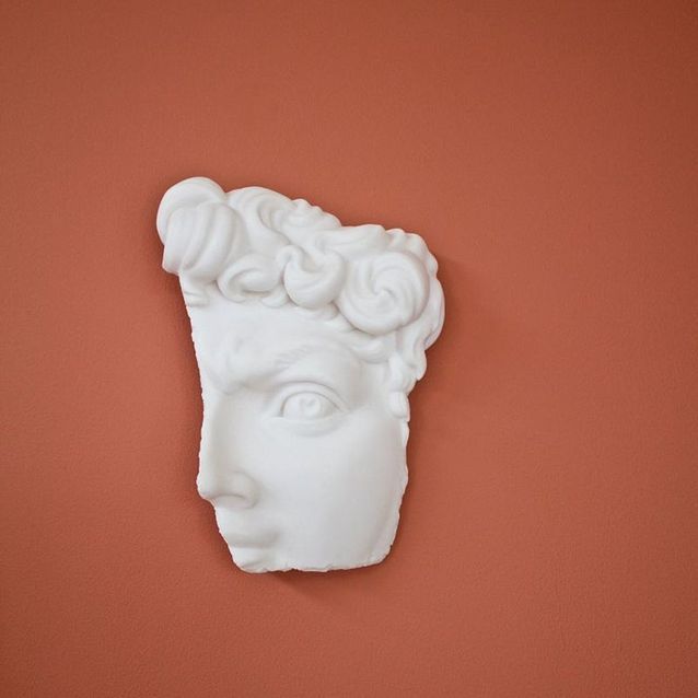 Para un efecto de museo, cuelgue un fragmento de una escultura en una pared de color