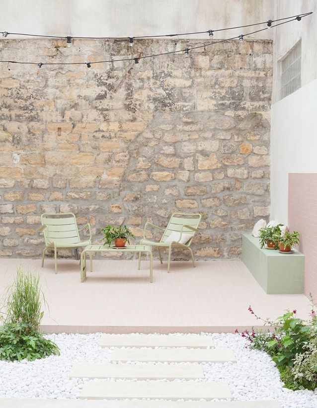 Combina muebles de exterior en colores pastel y paredes rugosas en el patio
