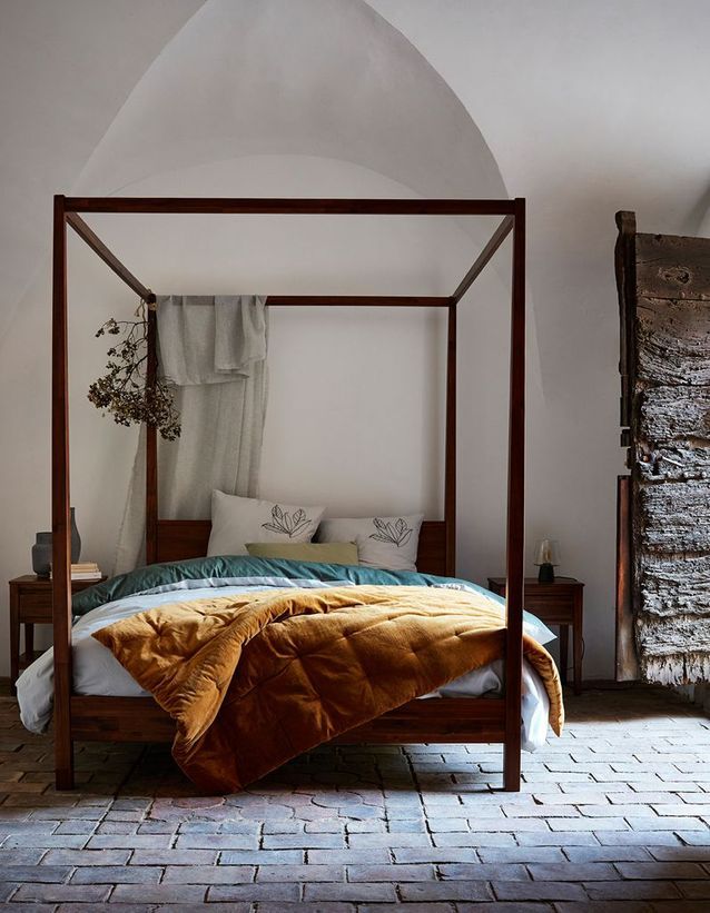 Cuelga flores secas en la cama con dosel del dormitorio.